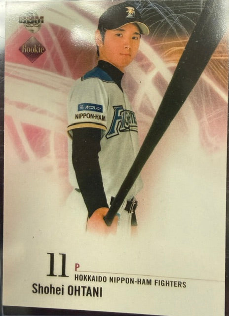 A collectible baseball trading card featuring Shohei Ohtani of the Hokkaido Nippon-Ham Fighters. The card shows a photo of Ohtani in his team uniform holding a bat, with his name and number printed at the bottom.