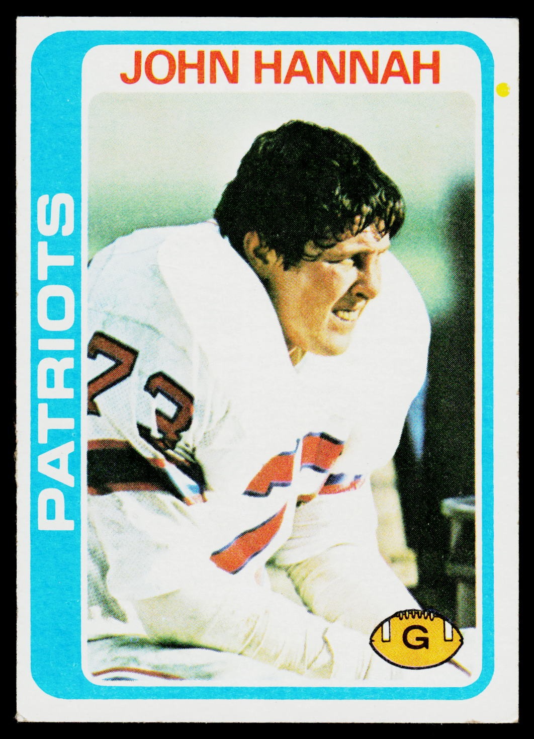 A vintage football trading card featuring John Hannah in a white uniform with red and blue numbers, bordered by a bright blue frame with 'PATRIOTS' on the left and 'JOHN HANNAH' at the top.