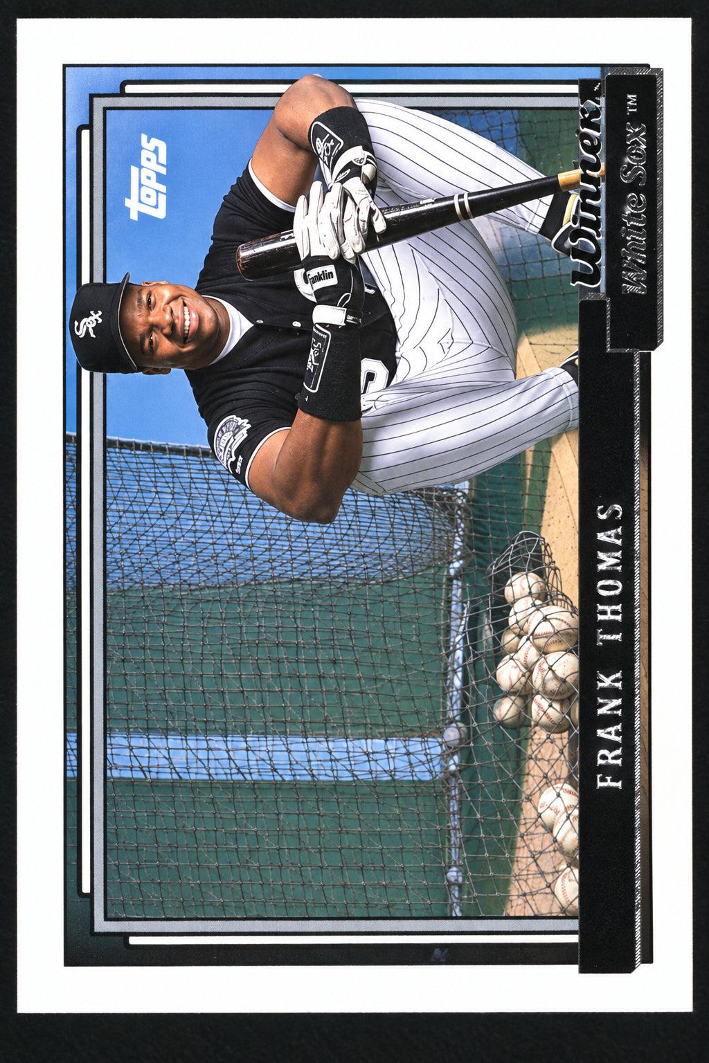 A vintage Topps baseball trading card featuring Frank Thomas, showing him batting in a dark indoor cage with a Topps logo in the upper left corner.