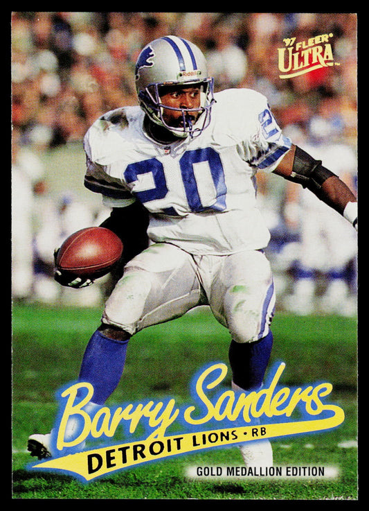 A vintage football trading card featuring Barry Sanders in a white Detroit Lions uniform with blue numbers and socks, running with a football on the field. The card includes the 'Flyer Ultra' logo at the top right and 'Barry Sanders Detroit Lions - RB' with 'Gold Medallion Edition' at the bottom.