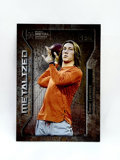 A Trevor Lawrence trading card from the 2012 Metal Universe Draft, featuring a photo of Lawrence in an orange long-sleeve shirt and white pants, set against a dark textured background with 'METALIZED' printed vertically on the left.