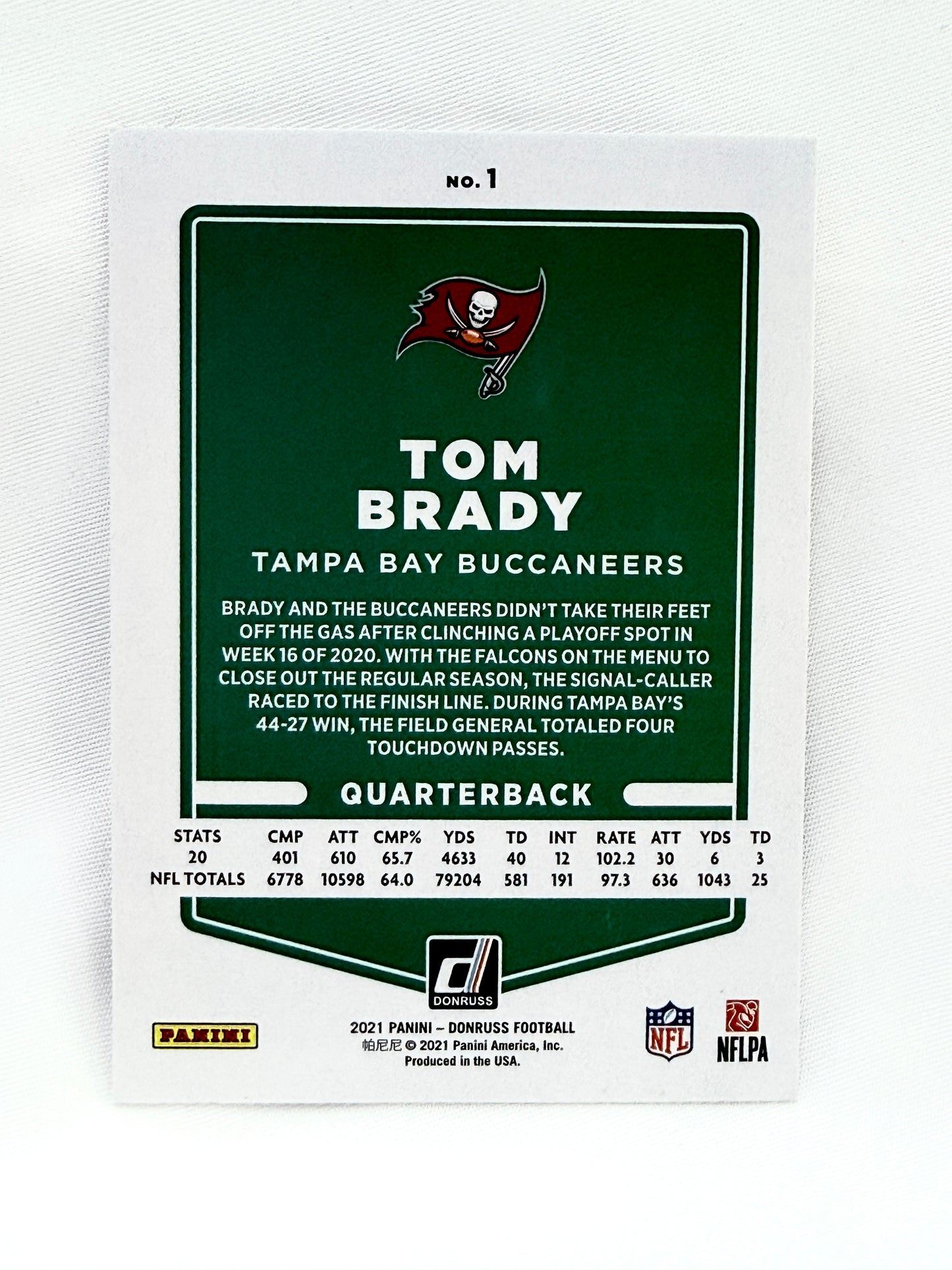 A collectible 2021 Panini Tom Brady Tampa Bay Buccaneers trading card, featuring a dark green and white design with player statistics and the Buccaneers logo.