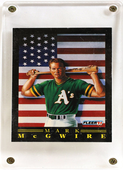 A Fleer baseball trading card of Mark McGwire mounted in a clear acrylic display block. The card features a portrait of McGwire in a green Oakland A's jersey holding a bat against an American flag background, with his name printed at the bottom.