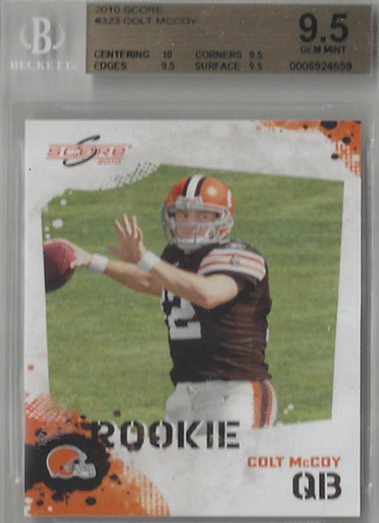 A graded rookie football trading card of Colt McCoy, sealed in a protective plastic slab. The card features a photo of McCoy in a brown and orange Cleveland Browns uniform, with 'ROOKIE' and 'COLT MCCOY QB' printed on a white, orange, and black splatter design.