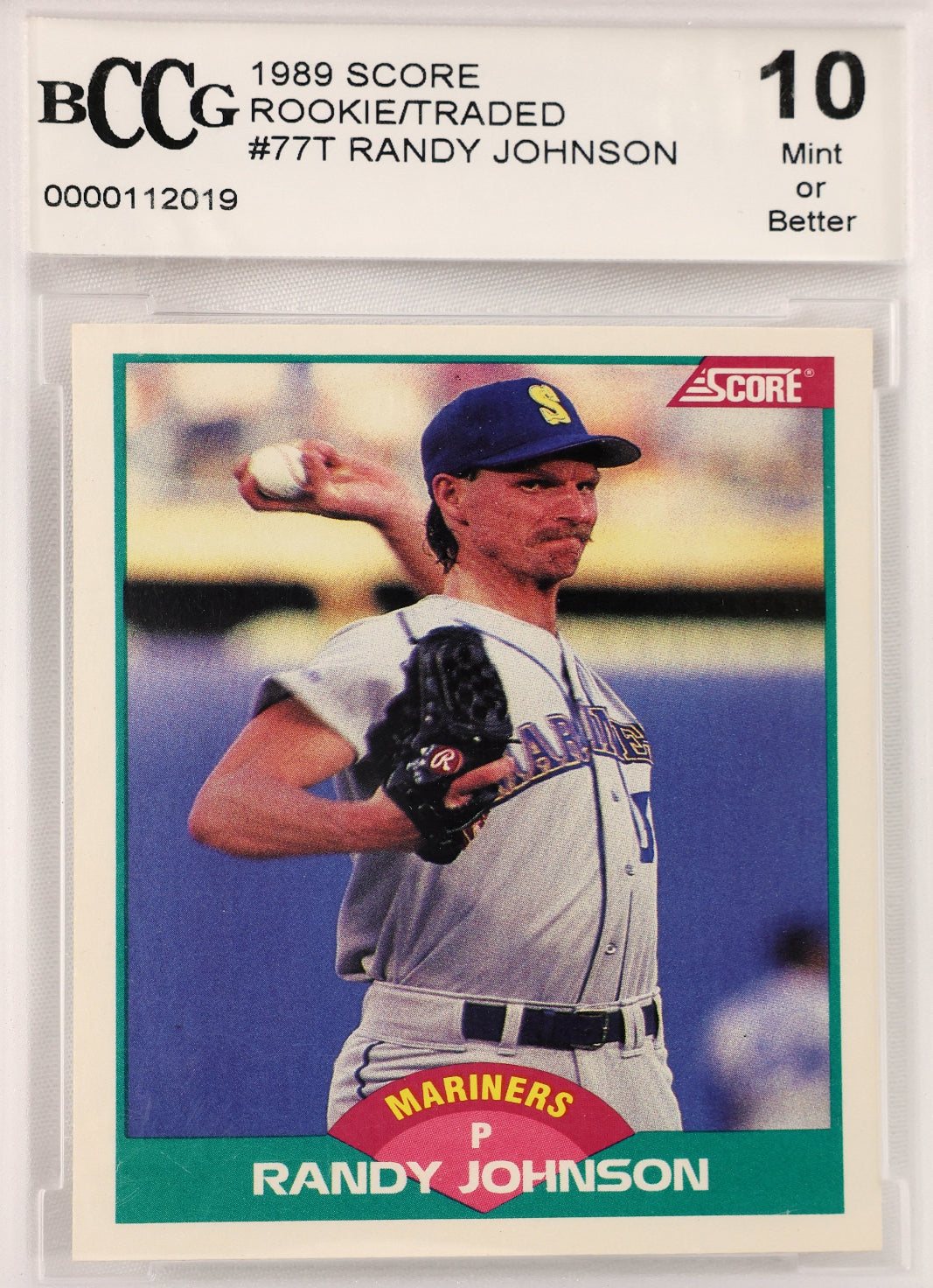 A graded 1989 Randy Johnson baseball trading card, rated 10 Mint or Better by BCCG. The card shows Randy Johnson pitching for the Mariners, with a blue cap, gray uniform, and green border on the card.