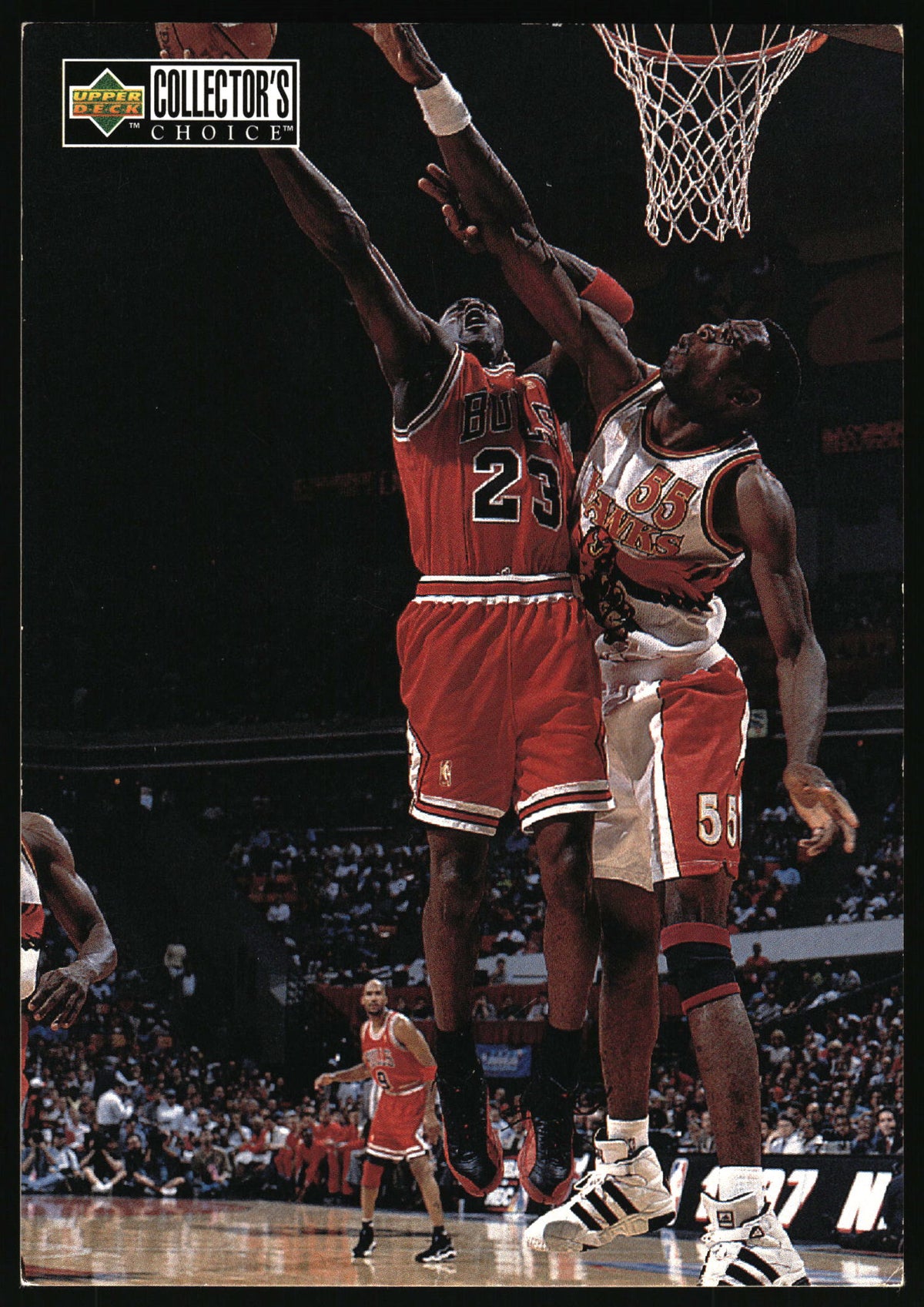 A basketball trading card featuring Michael Jordan in a red Chicago Bulls jersey jumping for a basketball, with another player in a white Bulls jersey defending him. The card has an 'Upper Deck Collector's Choice' logo in the top left corner.